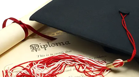 Graduation cap and diploma on table